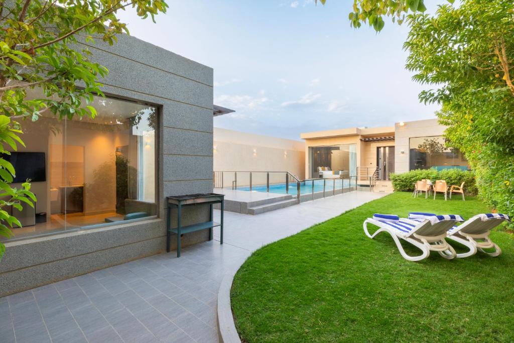 The Corner Hotel Resorts - Riyadh في الرياض: منزل مع حديقة وكرسيين في الفناء