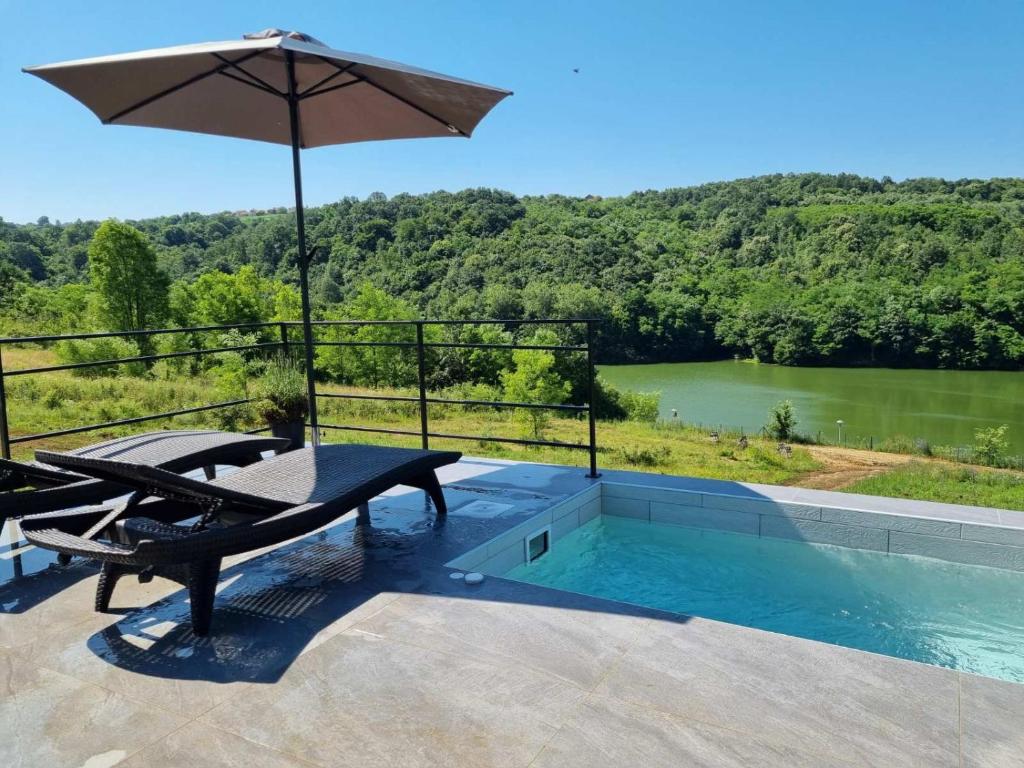 a patio with a table and an umbrella and a pool at Glamping A frame lake in Barajevo