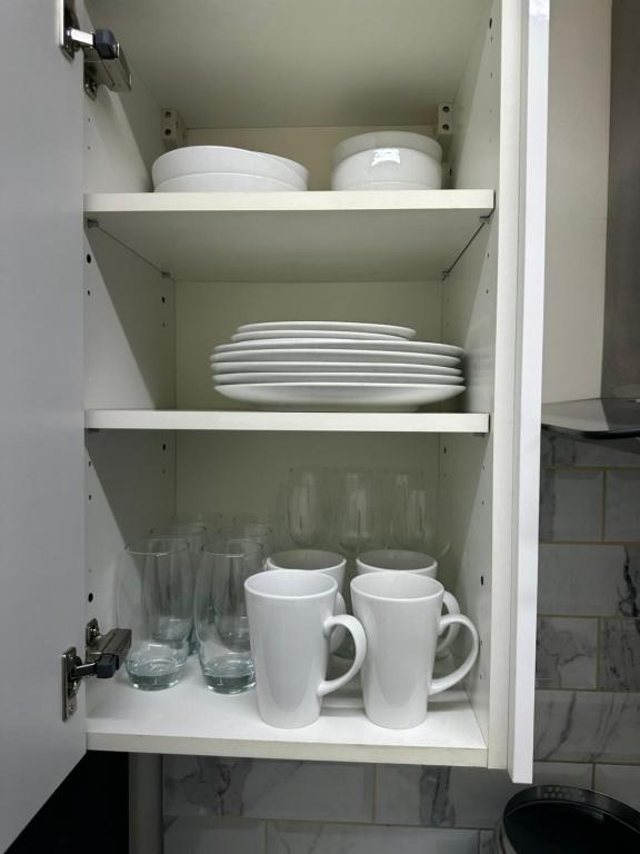 a cupboard filled with dishes and cups and plates at Stunning private room 2 in Bedford