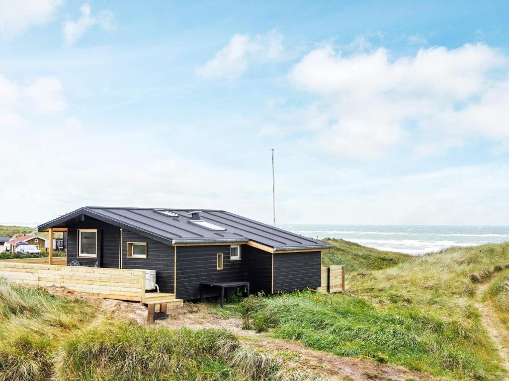 een zwart huis met zonnepanelen op een strand bij 4 person holiday home in L kken in Løkken