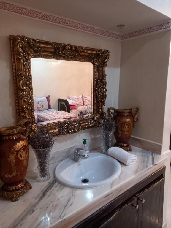 een badkamer met een witte wastafel en een spiegel bij Appartement abdessalam fetouaki in Moulay Yacoub
