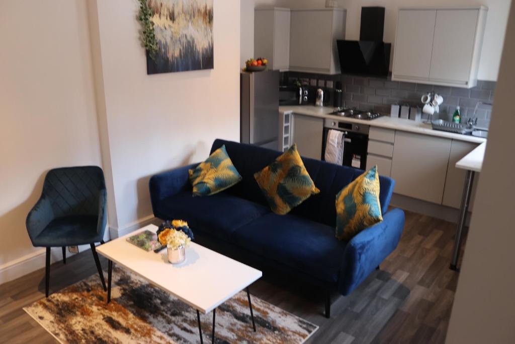 a living room with a blue couch and a table at Sandbach Apartments in Sandbach
