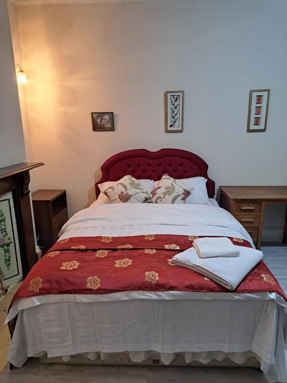 a bedroom with a large bed with a red blanket at Luxury 5 bedroom home near London Seven Kings Train station- 5 Room, 6 bed and sleeps 8 guest in London