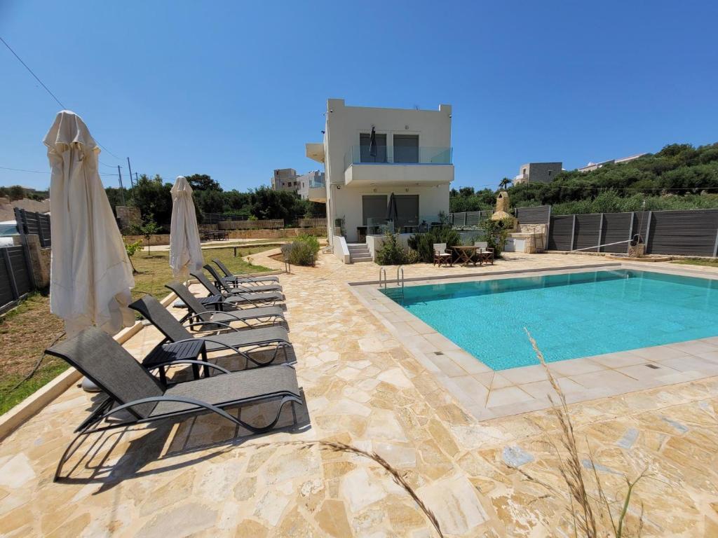 a group of lounge chairs next to a swimming pool at Horizon Villa Almyrida in Almirida