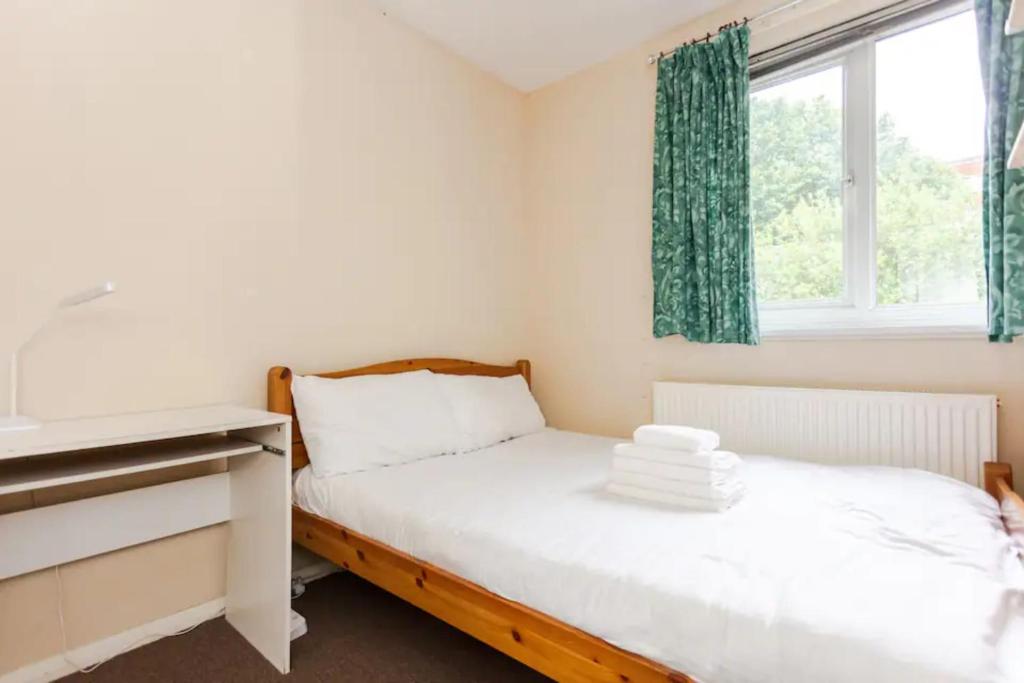 a bedroom with two beds and a desk and a window at Homely 3 Bedroom House with a Garden in London