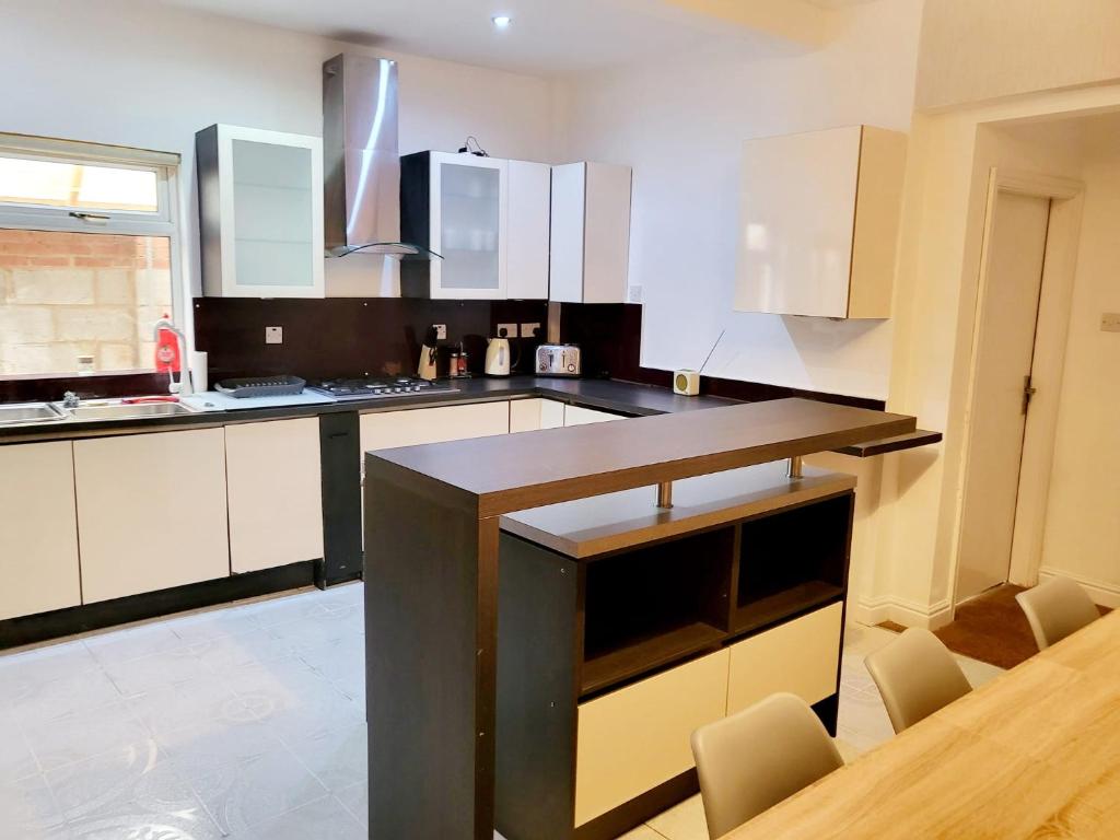 a kitchen with white cabinets and a wooden table at MM Short Stays in Birmingham