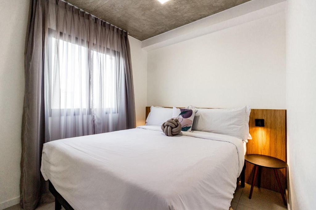 een slaapkamer met een groot wit bed en een raam bij Xtay BK30 Santana - Apartamentos decorados próximos ao metrô in Sao Paulo