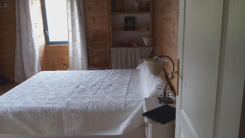 a bedroom with a white bed and a window at Ferme Racine in Jausiers