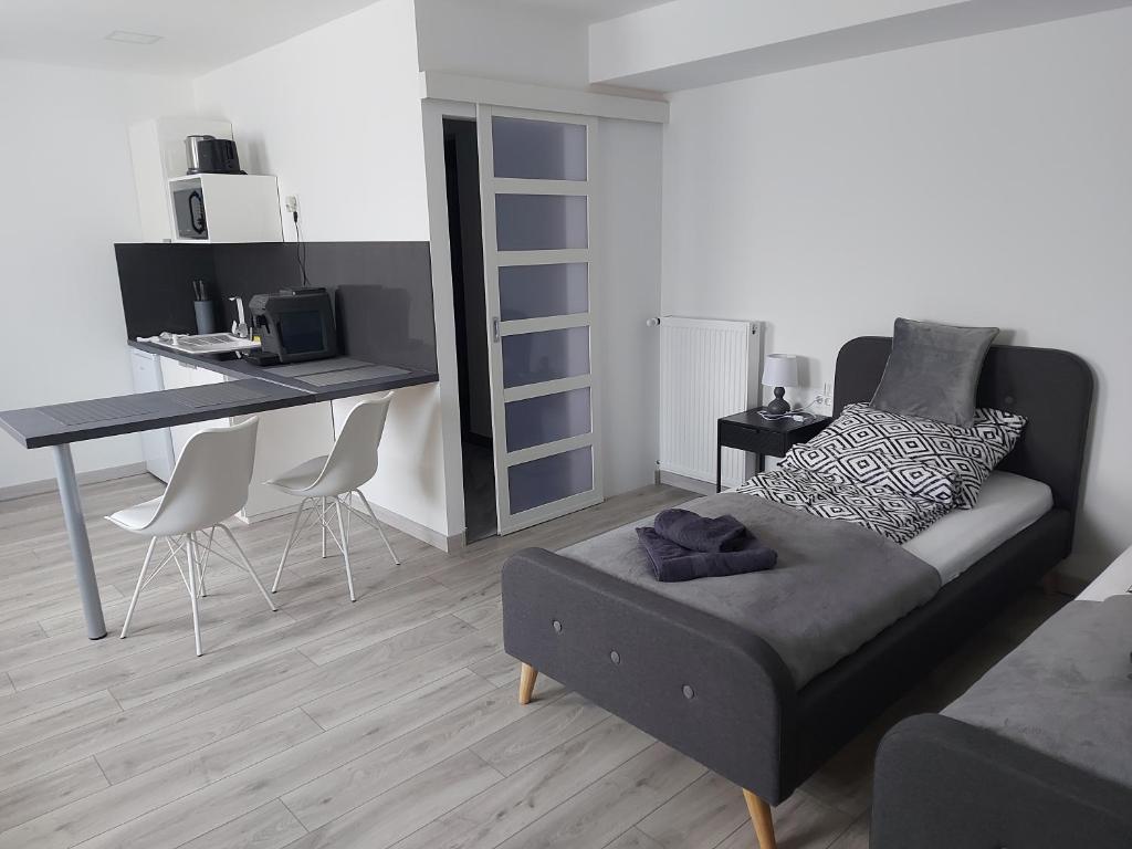 uma sala de estar com uma cama, uma mesa e cadeiras em Belvárosi apartmanház 2 em Szigetvár