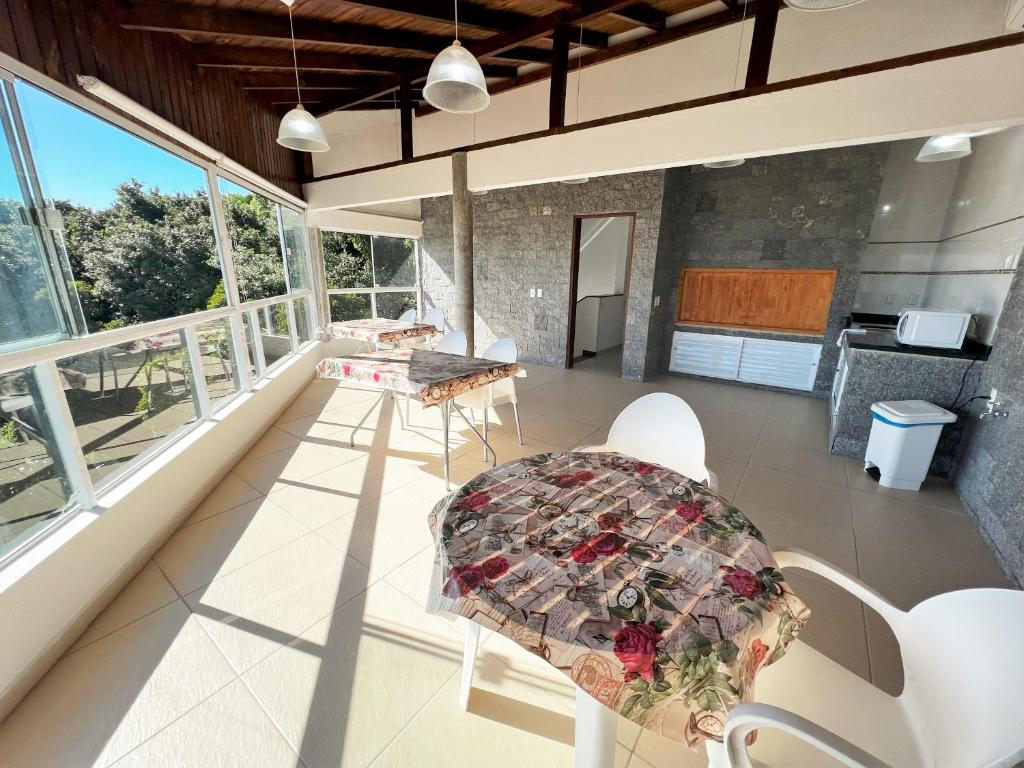 a room with a table and chairs on a balcony at Refúgio da Lagoinha - Centro de Bombinhas in Bombinhas