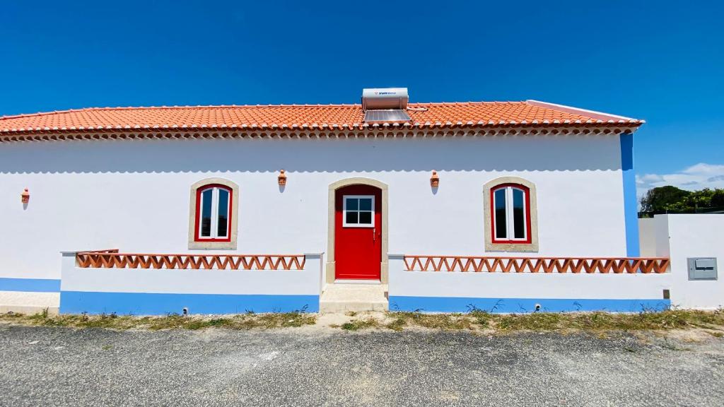 a white house with a red door at OceanLand - Santa Cruz in Santa Cruz