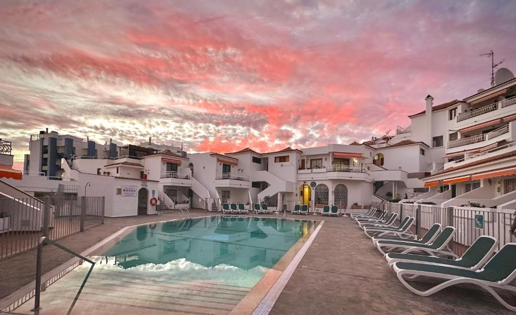 a swimming pool with lounge chairs in front of a building at Diamond Roof in Los Cristianos