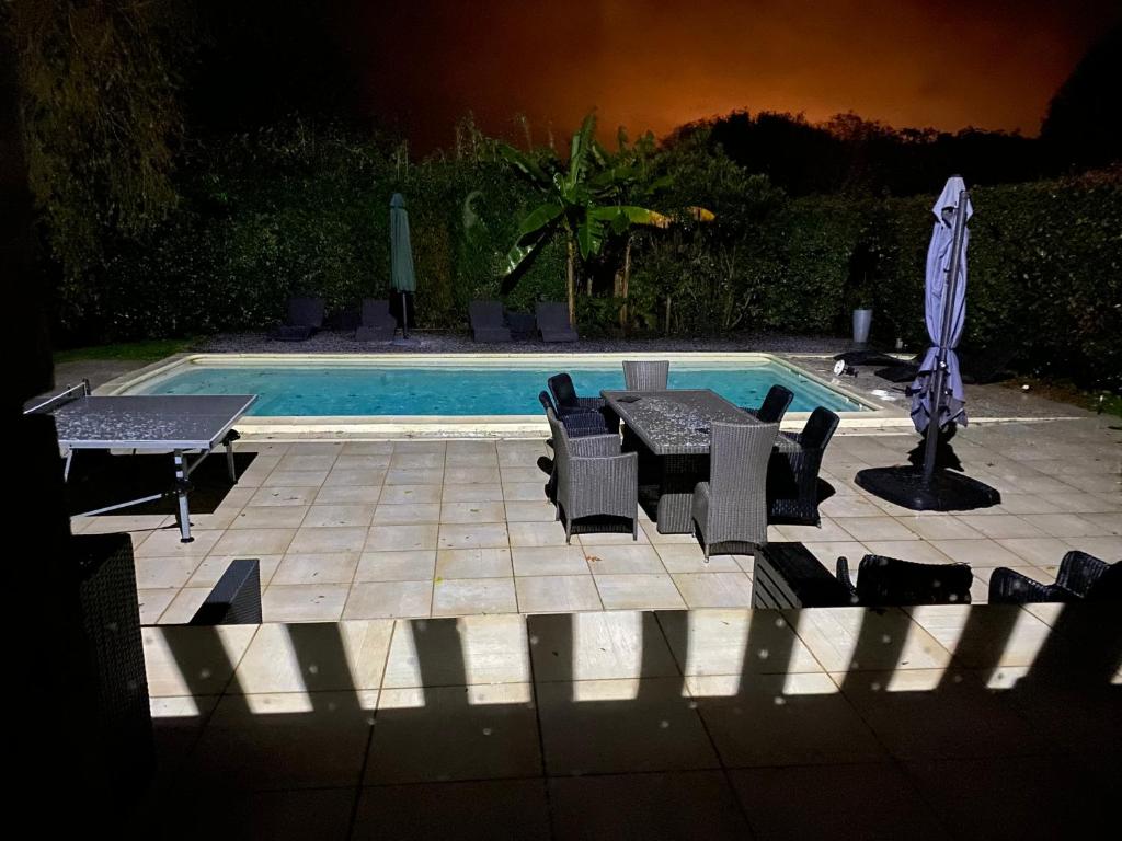 un patio con tavolo e sedie accanto alla piscina di SCI LOUXOR BY DOMINIQUE a Urrugne