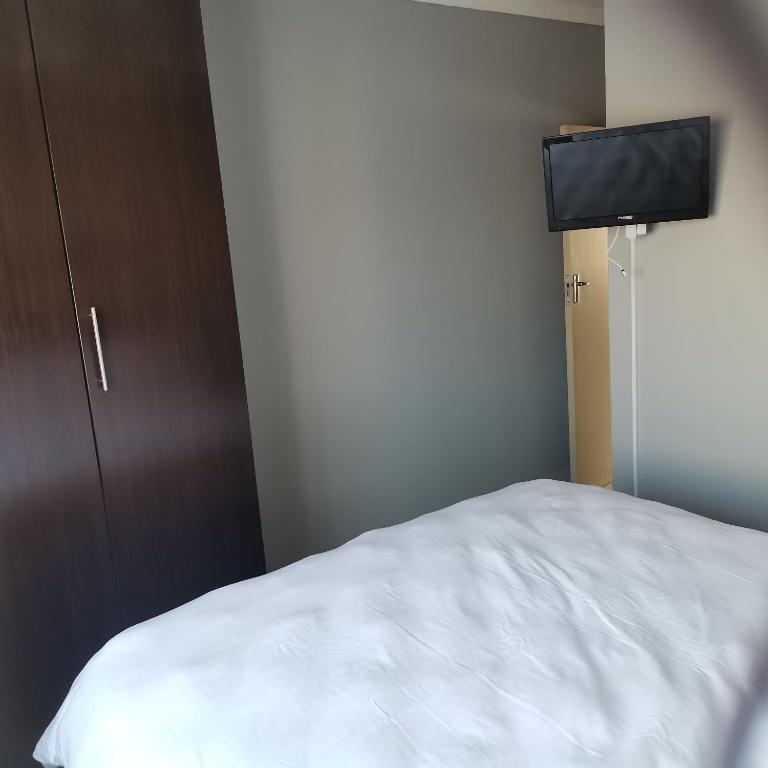 Pablo and Sons Apartments في بولوكوان: غرفة نوم بسرير ابيض وتلفزيون بشاشة مسطحة