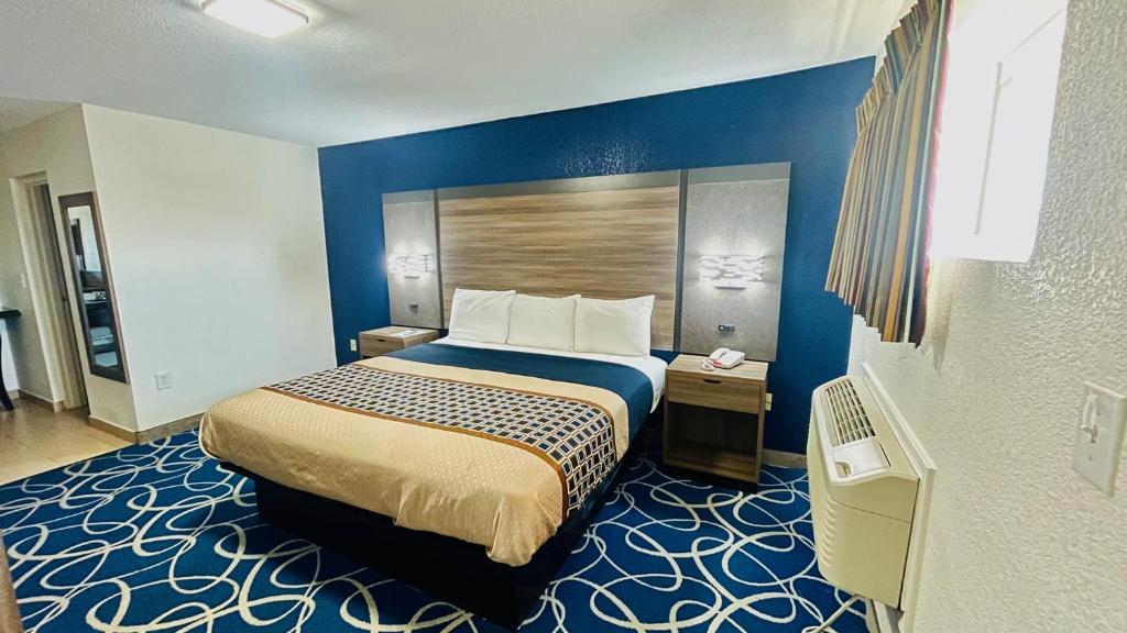 a hotel room with a bed and a blue wall at Budget Inn Pecos in Pecos