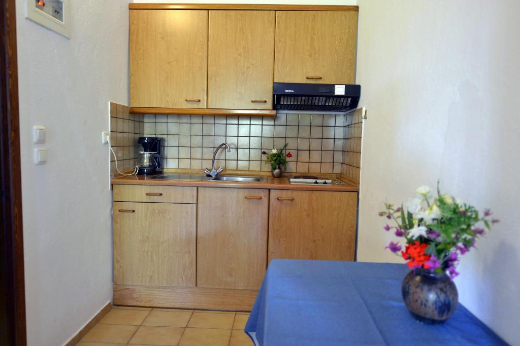 a kitchen with wooden cabinets and a table with a vase of flowers at Haus Katerina in Vourvourou