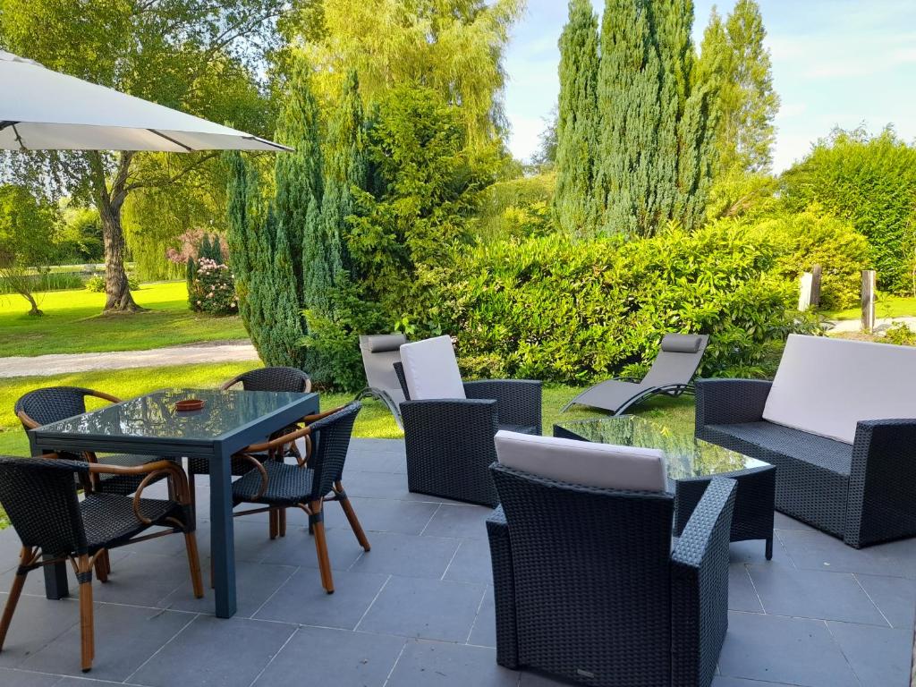 eine Terrasse mit Stühlen, Tischen und einem Sonnenschirm in der Unterkunft Domaine de l'Ermitage in Rue