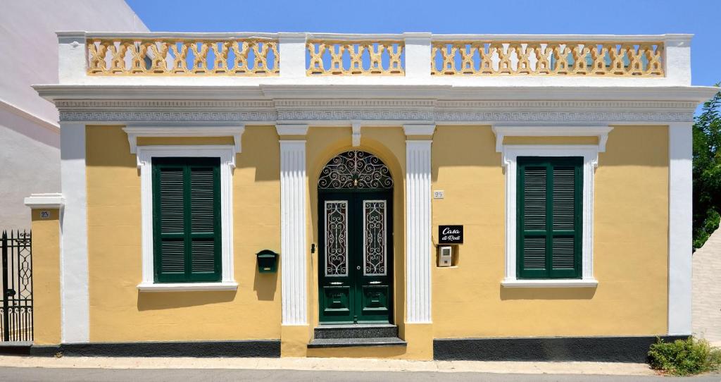 ein gelbes Haus mit grünen Türen und einem Balkon in der Unterkunft Casa Di Rodi in Rhodos (Stadt)