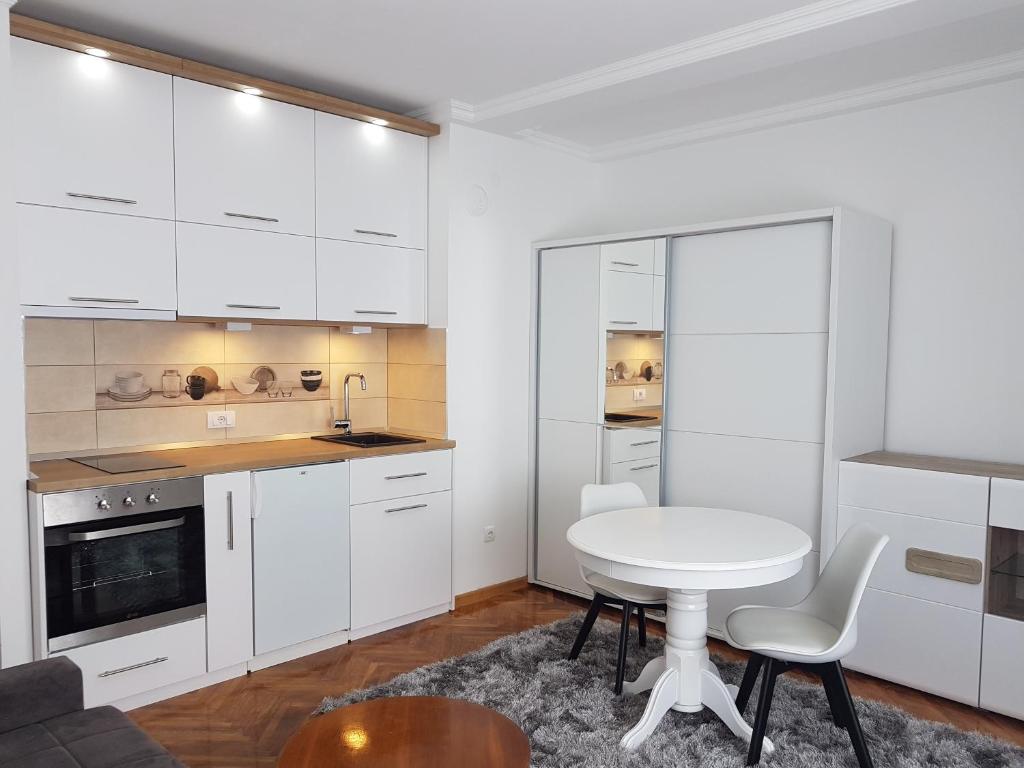 a kitchen with white cabinets and a table and chairs at Emili apartment in Belgrade