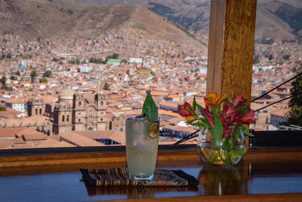 a table with a drink and a vase with flowers at Inkantari Boutique Hotel in Cusco