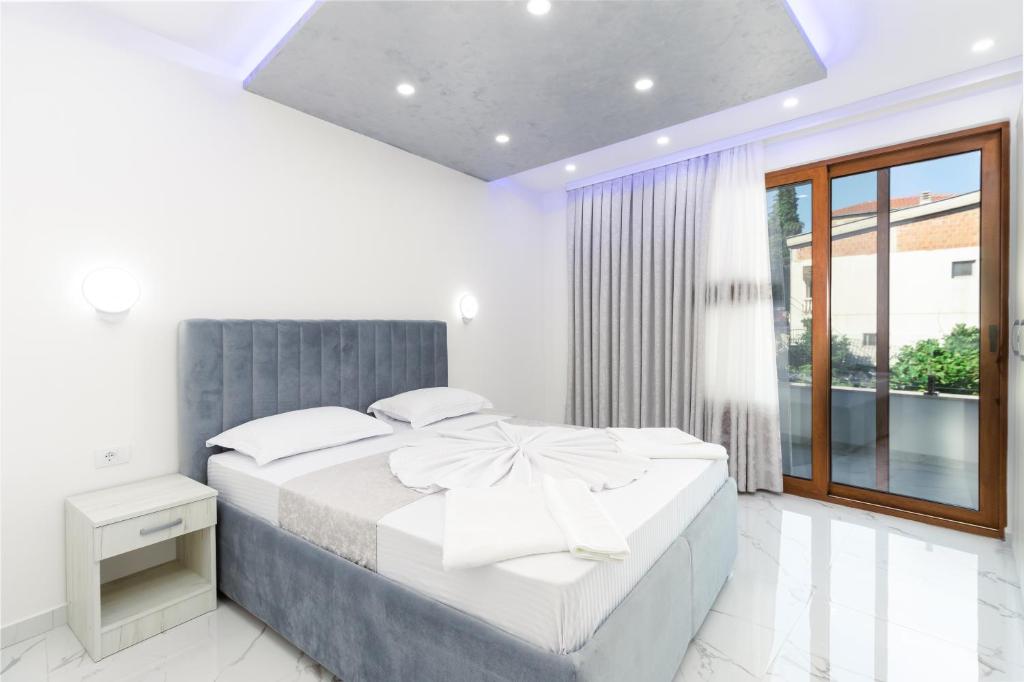 a white bedroom with a large bed and a window at Apart-Hotel President in Ulcinj