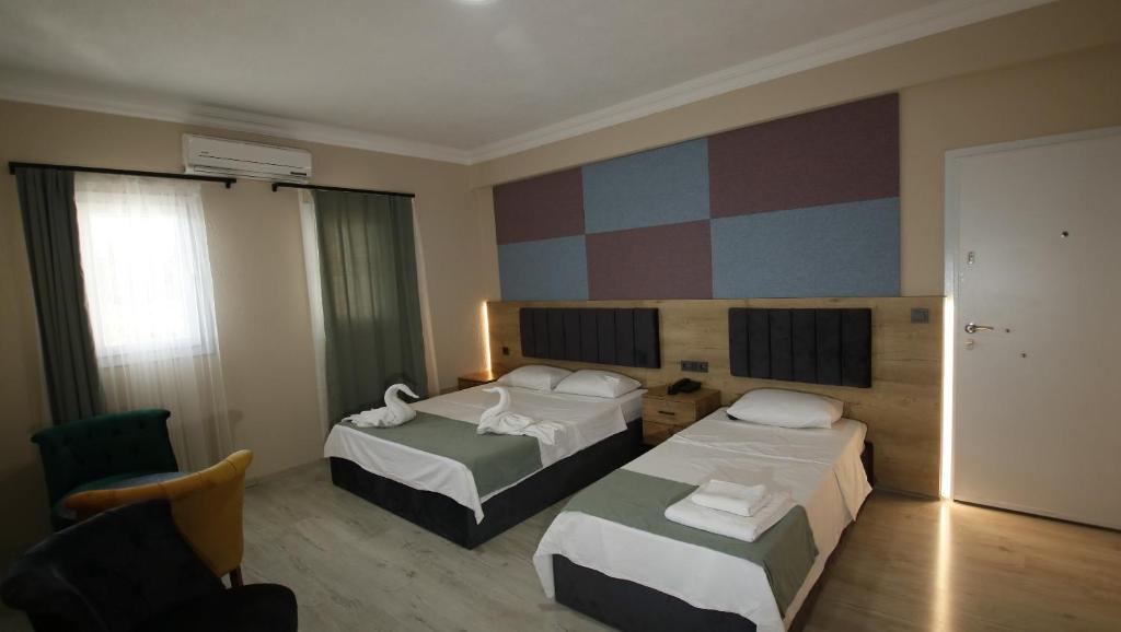 a hotel room with two beds and a chair at Seydikemer Yıldız hotel 