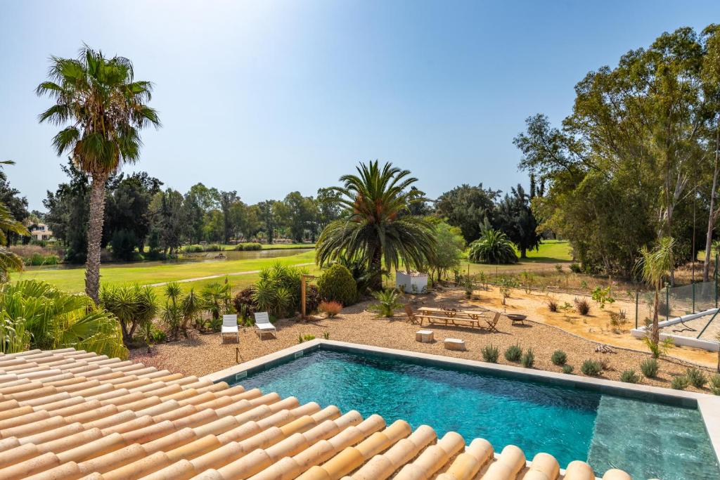 - une piscine dans une cour avec des palmiers dans l'établissement Penina Golf - Villa de luxe em Alvor no Algarve, à Portimão
