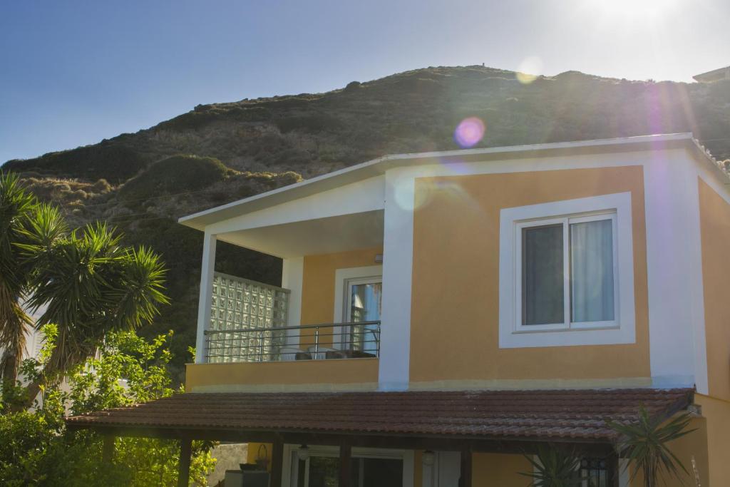 a yellow house with a mountain in the background at Villa Giorgos in Kefalos