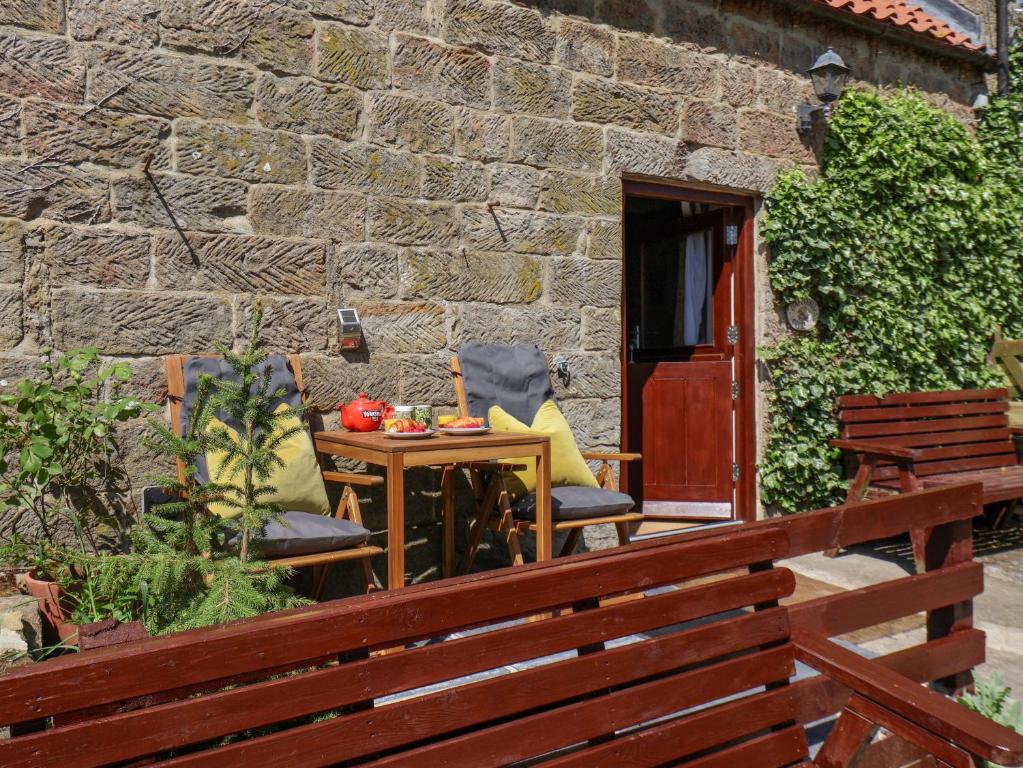 a patio with two chairs and a table and a brick wall at Daffodil Cottage in Danby
