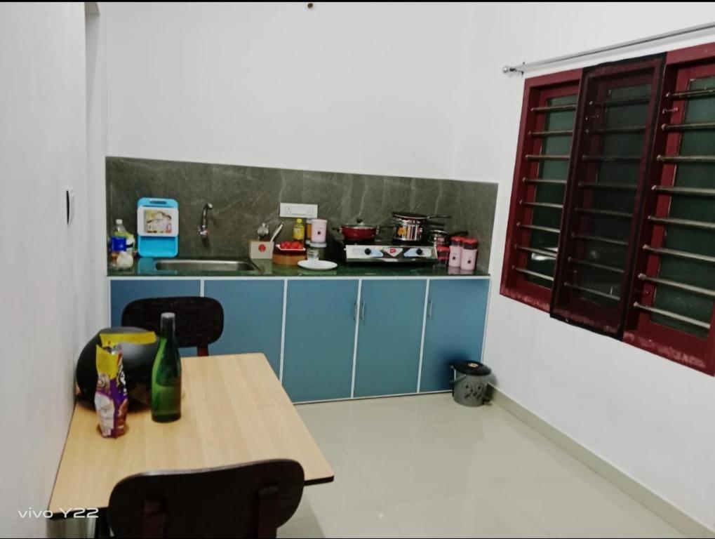 een keuken met blauwe kasten en een tafel en stoelen bij Micro homestay mulavukad in Ernakulam