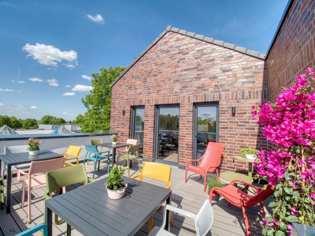 een patio met tafels, stoelen en bloemen bij Gästehaus linda&otto in Achim