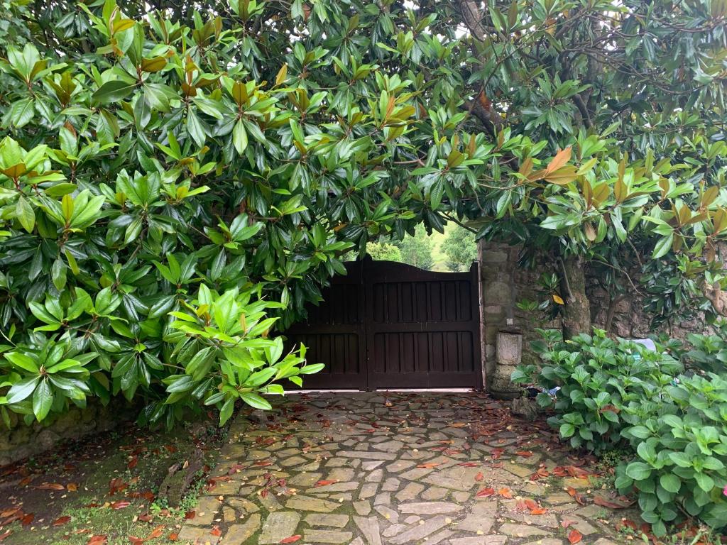 a wooden gate under a tree with a stone walkway at Casa Rural Erre Q Erre in Oreña