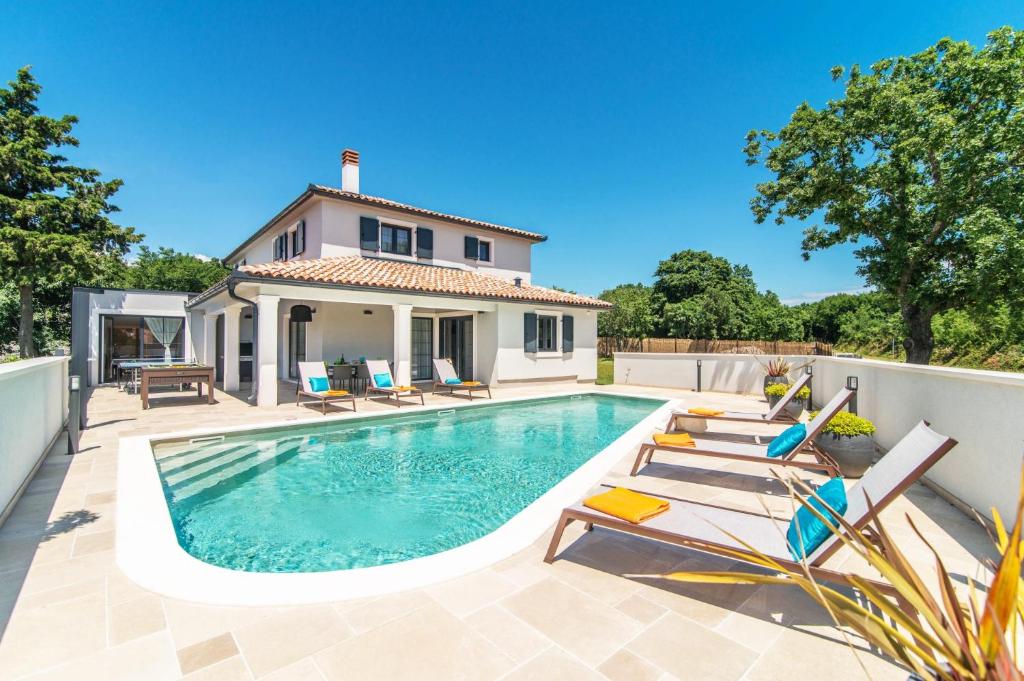 een zwembad met stoelen en een huis bij Villa Prodol by Villa Plus in Manjadvorci