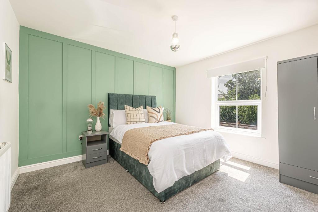 a bedroom with a bed with a green wall at Charming 3-Bedroom Home in Historic Lincoln Ideal for Families in Lincolnshire