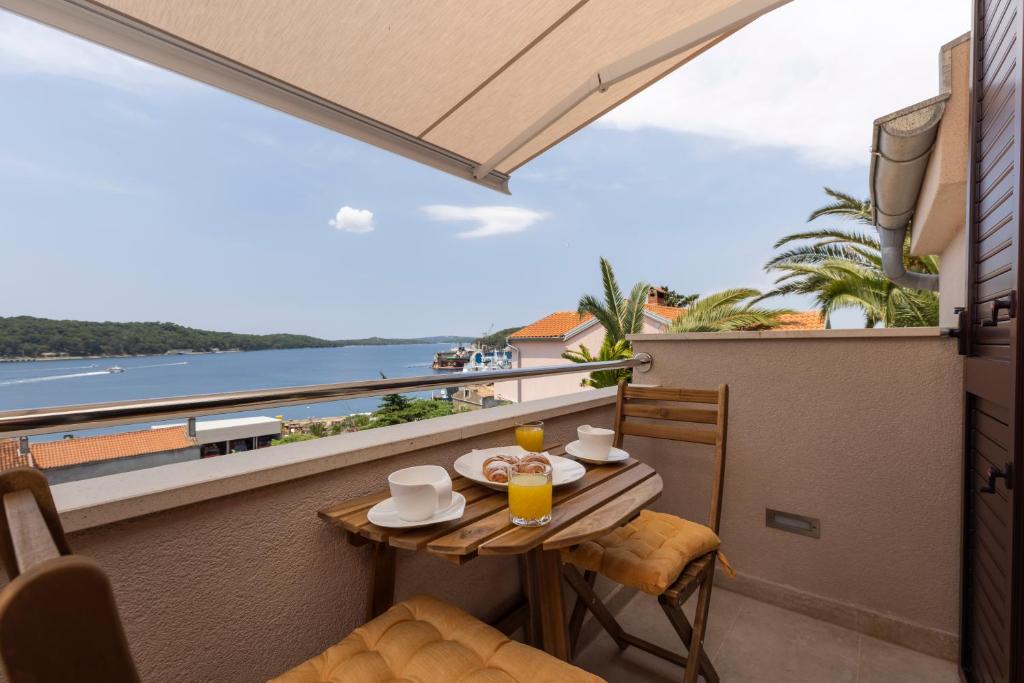 balcón con mesa y vistas al océano en Easy, en Mali Lošinj