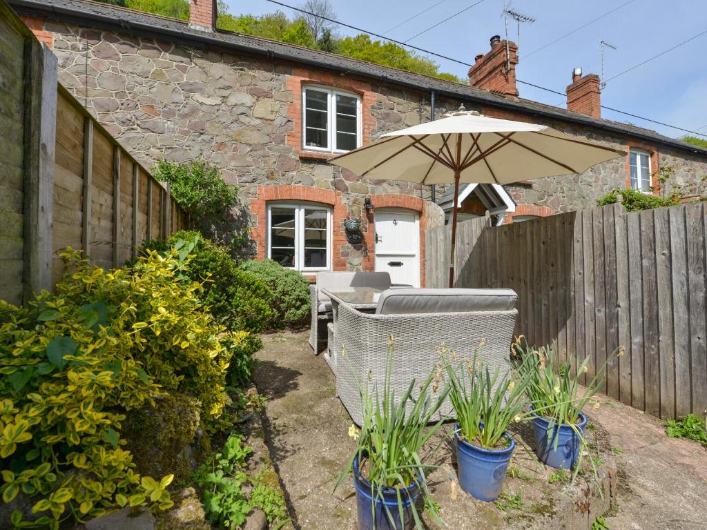 eine Terrasse mit einem Sonnenschirm, Stühlen und Pflanzen in der Unterkunft Woodedge in Minehead