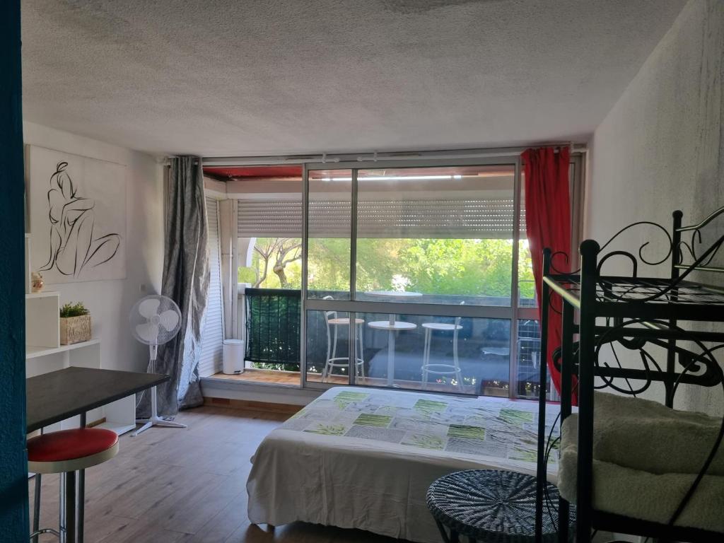 une chambre avec un lit et une grande fenêtre dans l'établissement Idéal Vacances petit budget, à La Grande Motte
