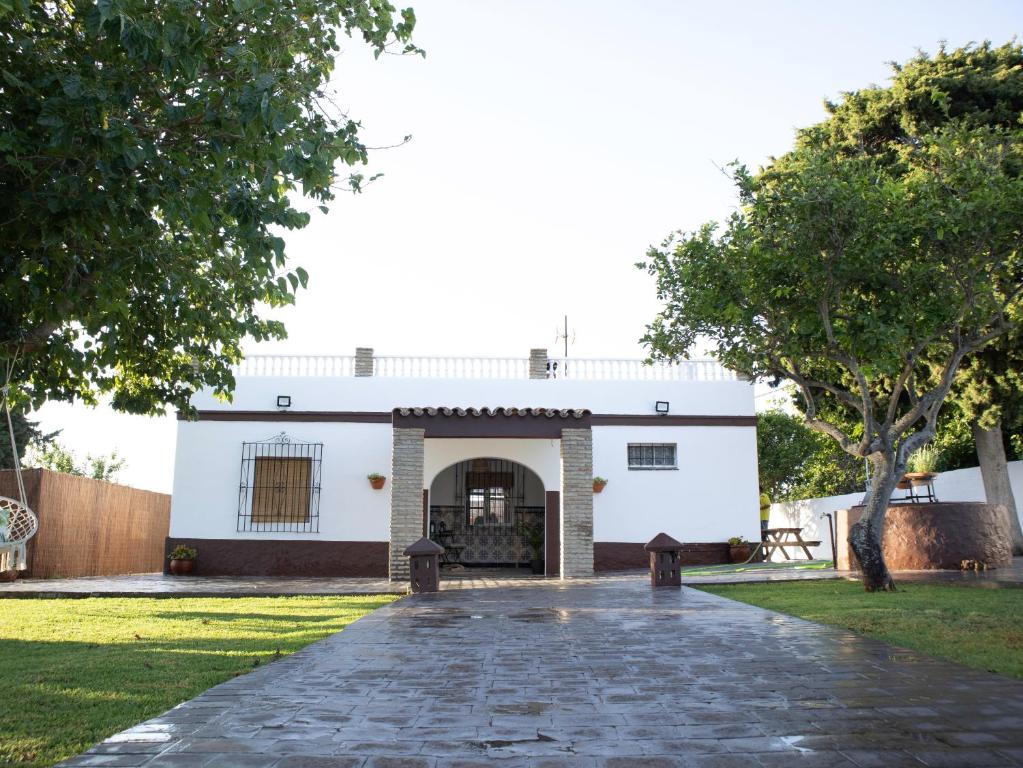 a white building with a cobblestone driveway at Villa Alegría in Chiclana de la Frontera