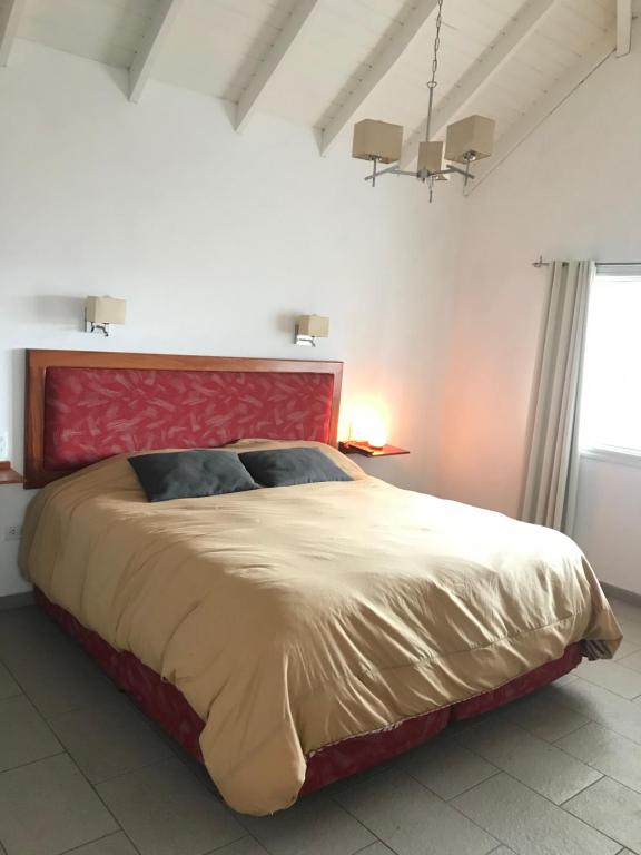 a bedroom with a large bed with a red headboard at Apart Jazmines del Río in Santa Rosa de Calamuchita