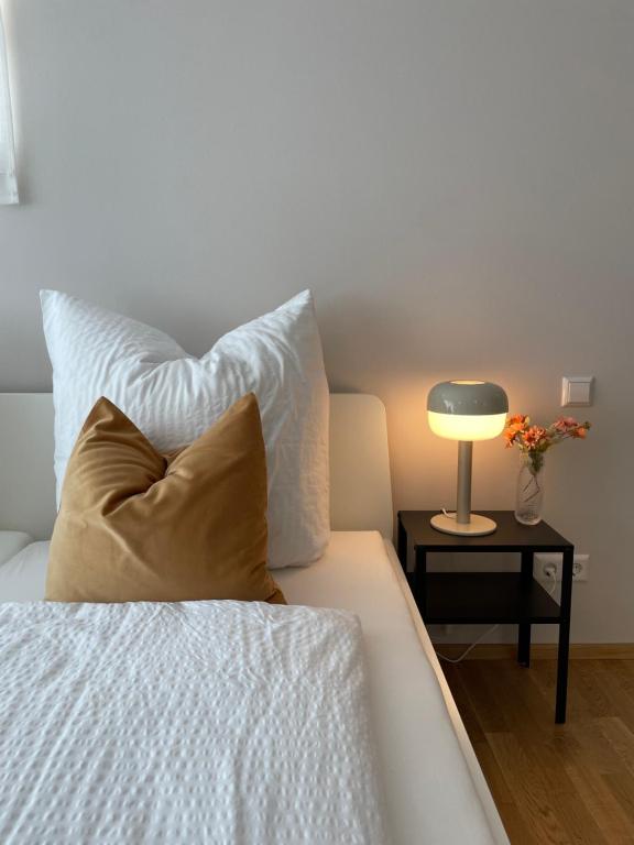 Cama con almohada y mesa con lámpara en Hugo Inn 2, en Stockach