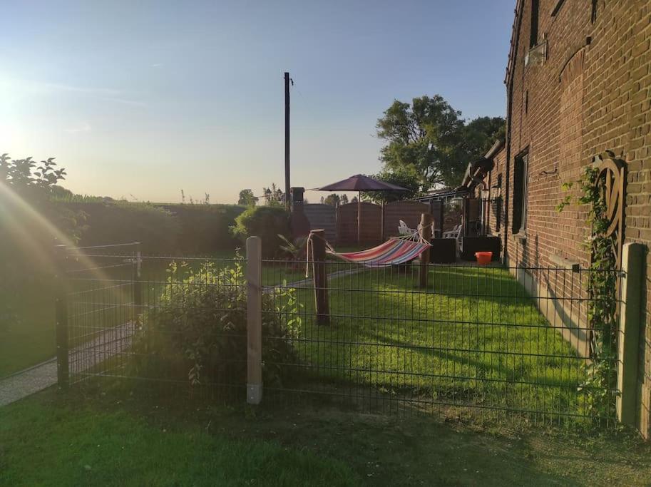 une clôture avec un hamac en face d'un bâtiment dans l'établissement Ferienwohnung im Grünen, à Geldern