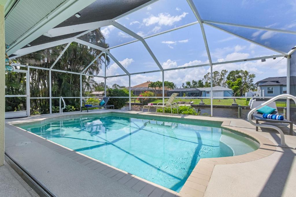 a large swimming pool with a large glassconservatory at Serene canal, three bedrooms and a large pool! - Villa La Brisa Fresca in Cape Coral