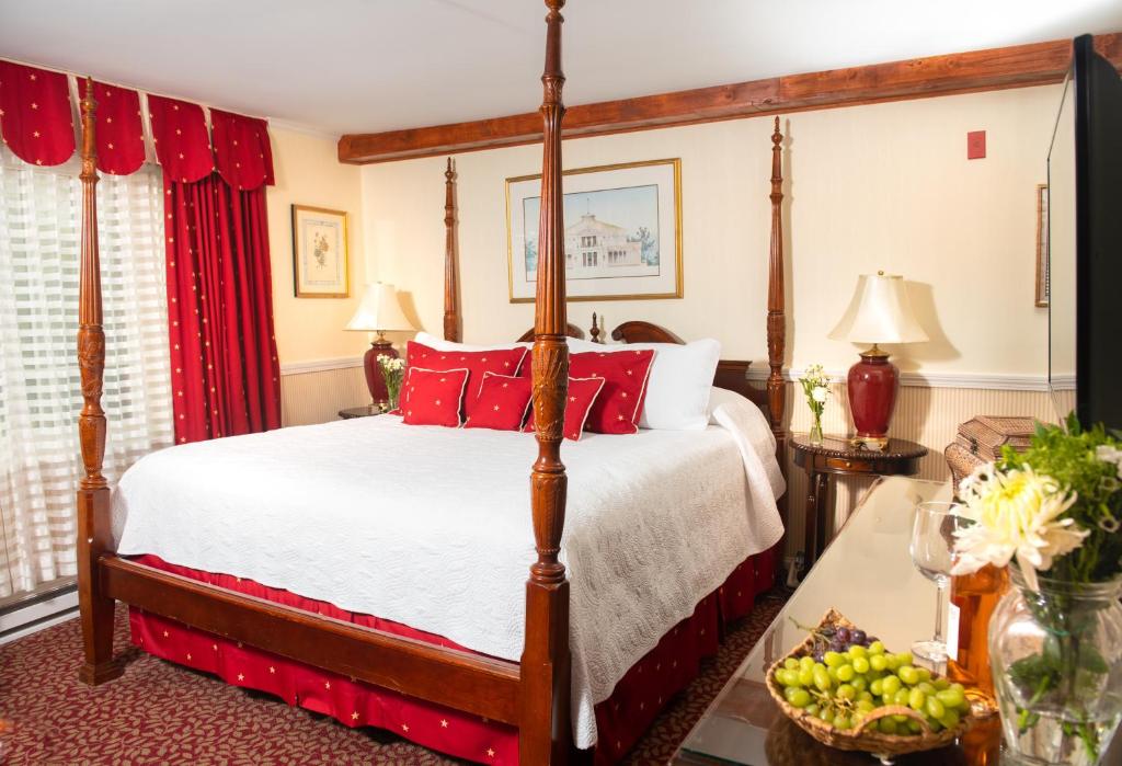 Schlafzimmer mit Himmelbett und roten Kissen in der Unterkunft America's Cup Inn Newport in Newport