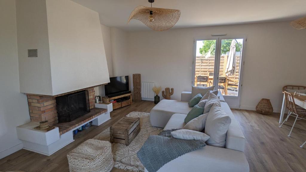 un salon avec un canapé blanc et une cheminée dans l'établissement Maison au calme proche de l'océan et du golf, à Talmont-Saint-Hilaire