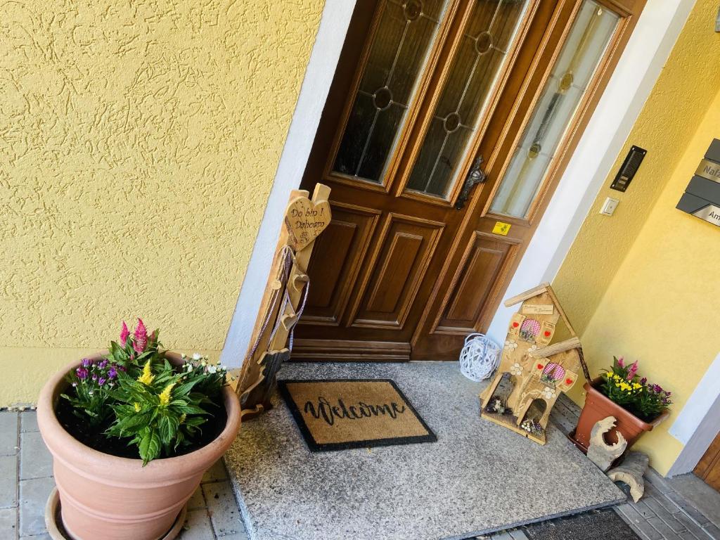 a door with a potted plant and a welcome sign in front at Fewo mit Burgruinenblick in Runding