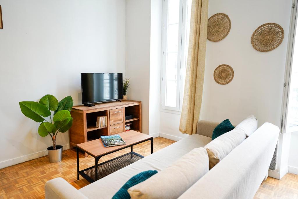 un salon avec un canapé blanc et une télévision dans l'établissement Une Pause quelque part, à Marseille