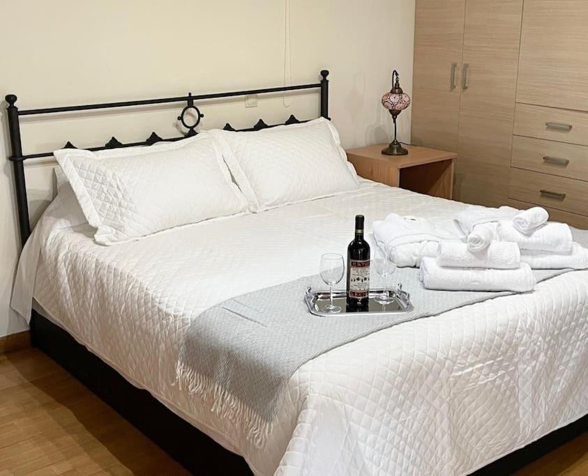 a white bed with a bottle of wine and towels at Sweet Makri Suite in Nea Makri