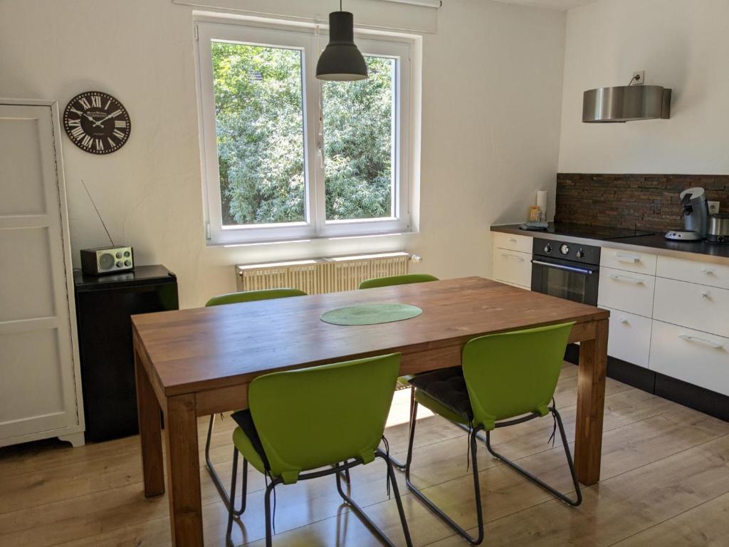 cocina con mesa de madera y sillas verdes en Gartenblick, en Reichenberg