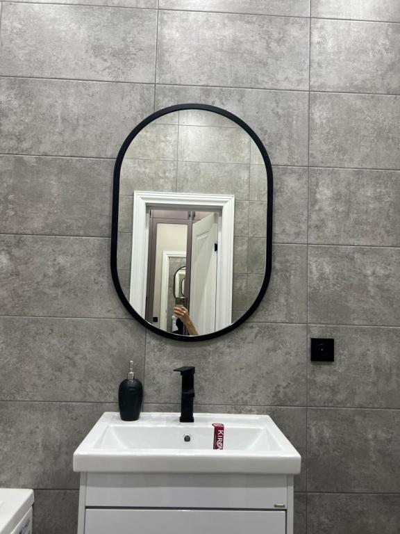 a bathroom with a sink and a mirror on a wall at Люксовая Квартира in Aktobe