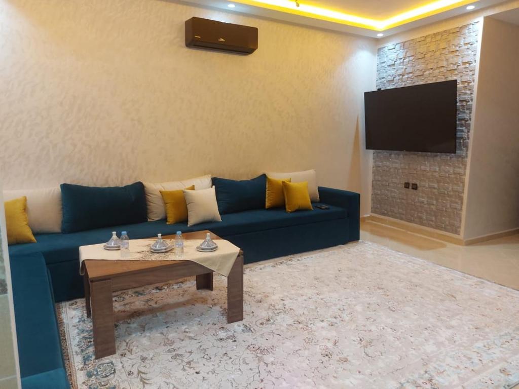 a living room with a blue couch and a table at L'horizon Aéroport Appartement in Marrakech